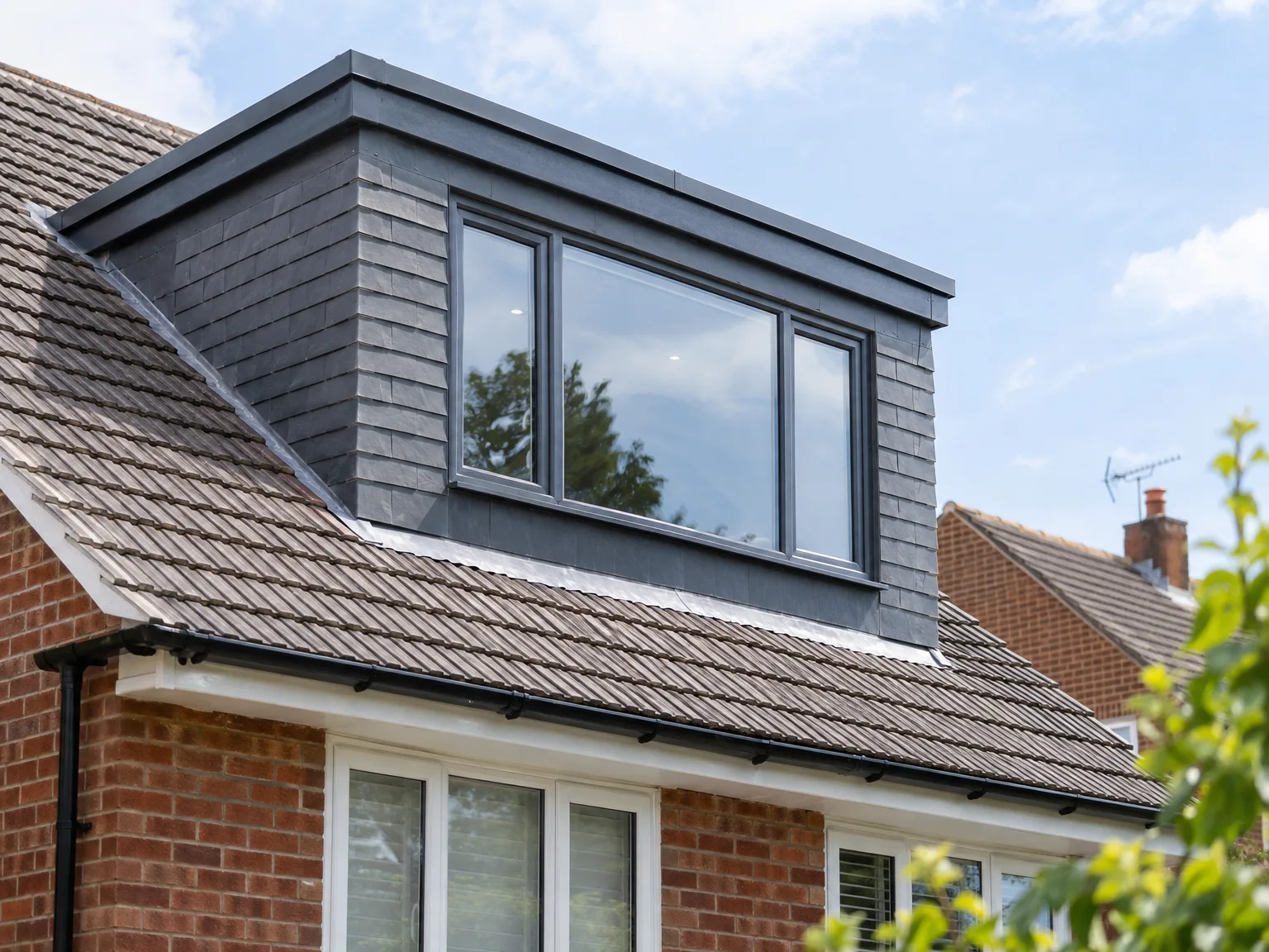 Dormer loft conversion with dark timber-clad walls and large windows on pitched brick roof