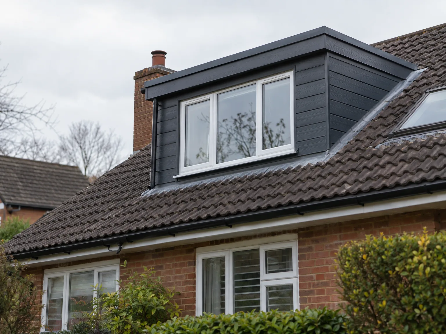 Completed dormer loft conversion with white-framed windows on brick home