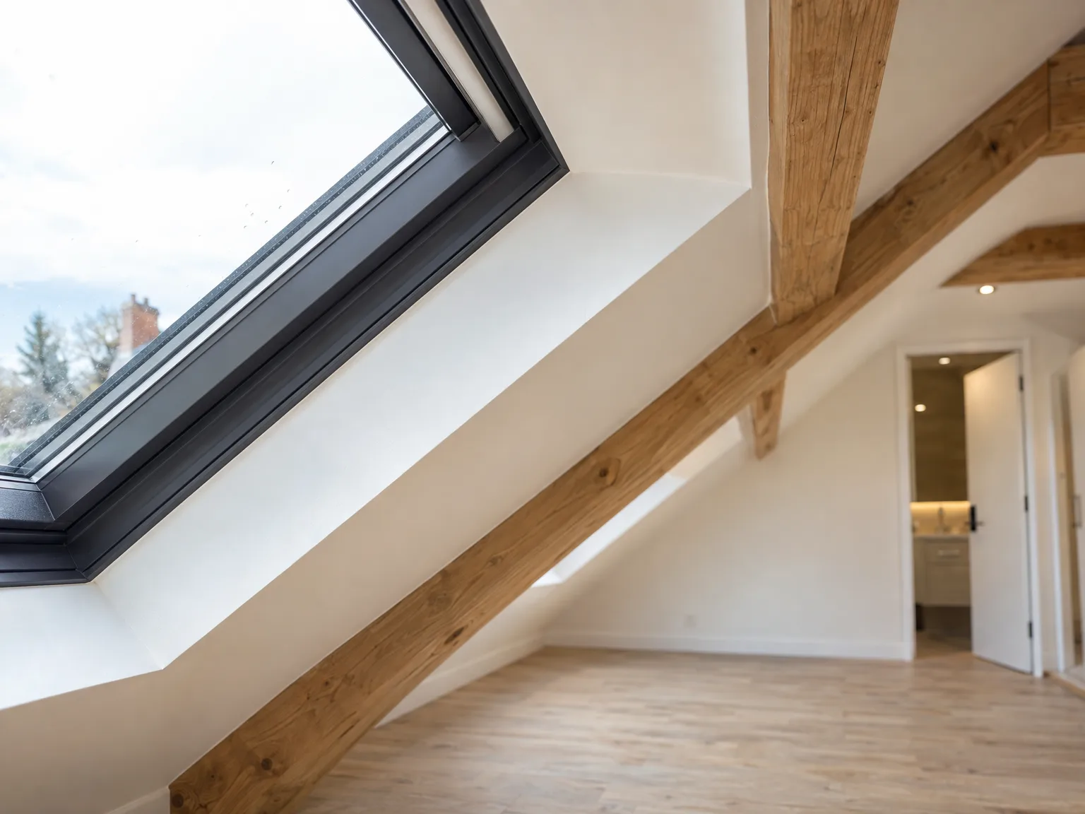 Modern Loft Conversion featuring wooden beams, white walls and roof skylight