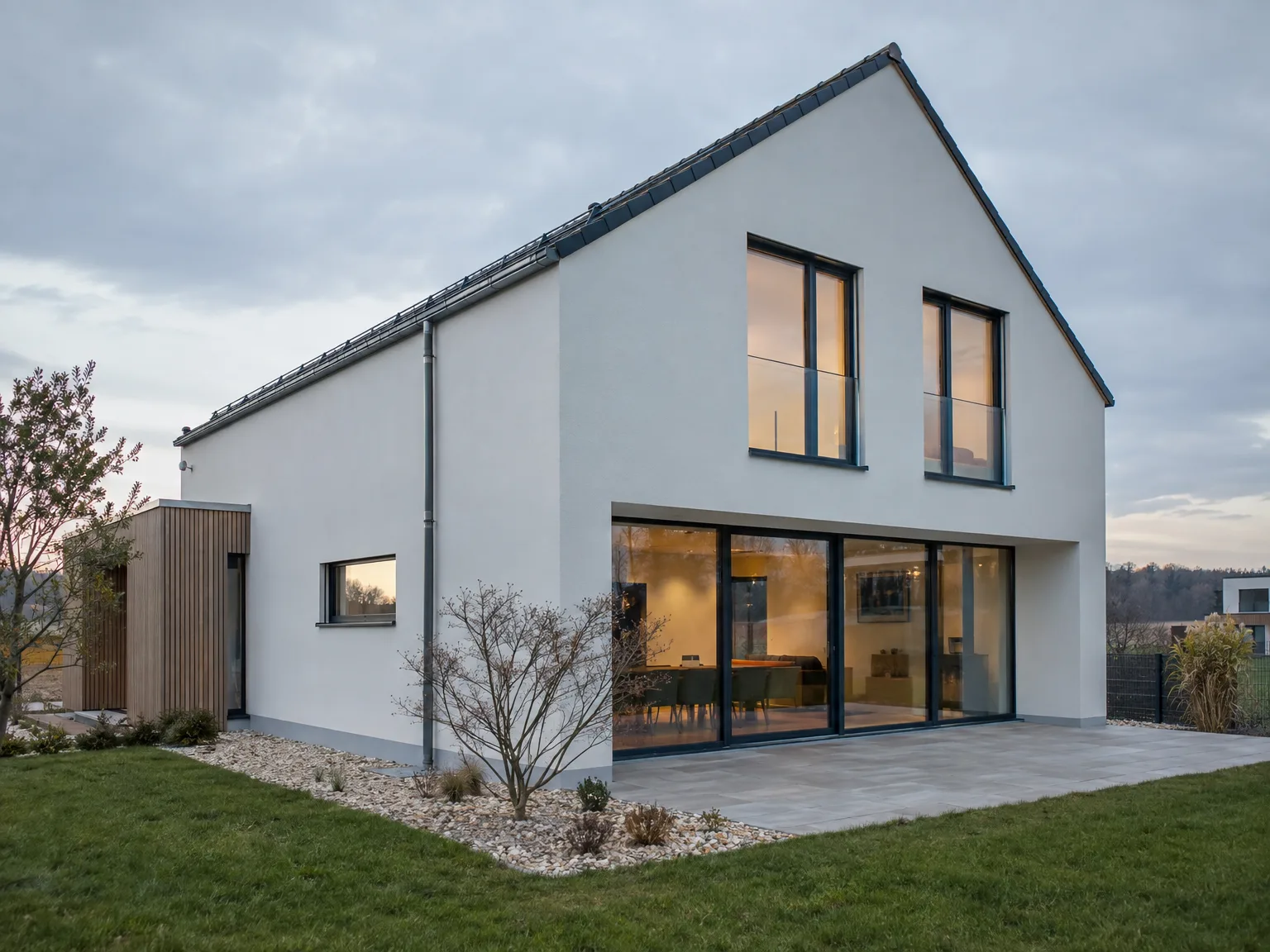 Contemporary white-rendered new build home with black windows and expansive glass sliding doors to terrace